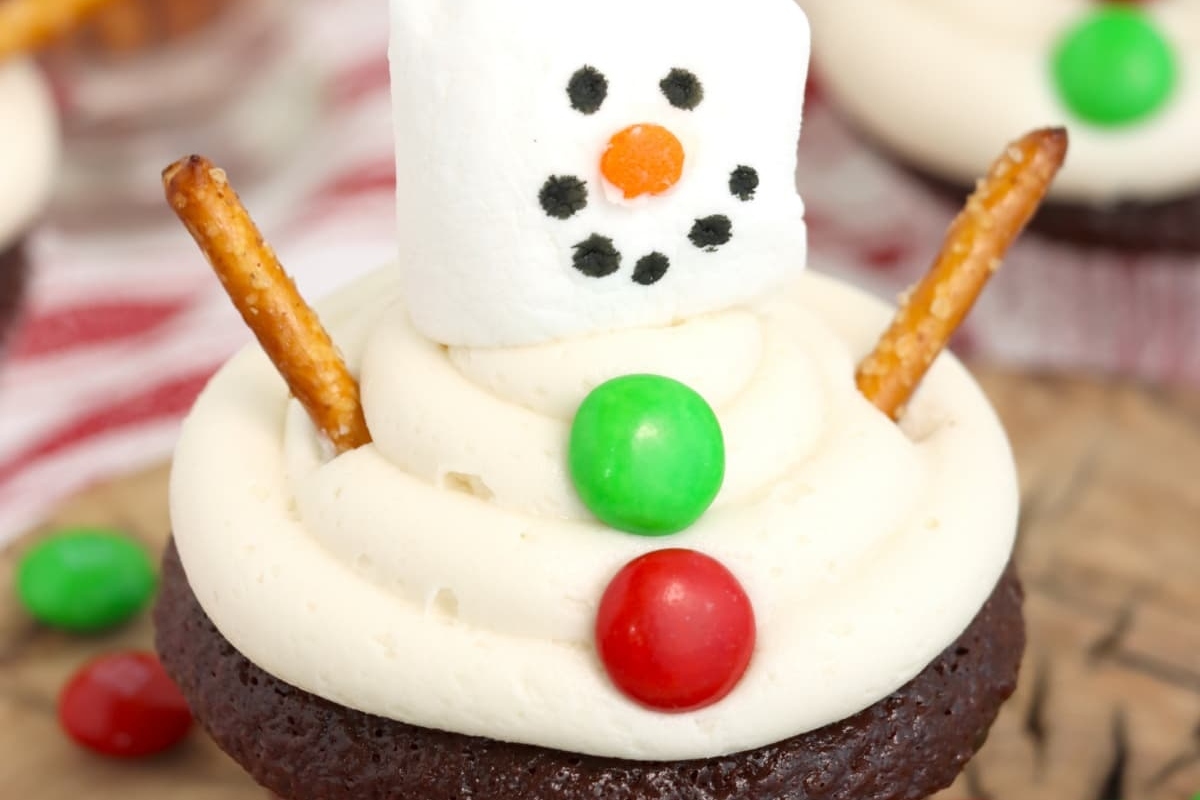Cute Christmas cupcakes featuring snowmen with candy cane arms and pretzel hats.