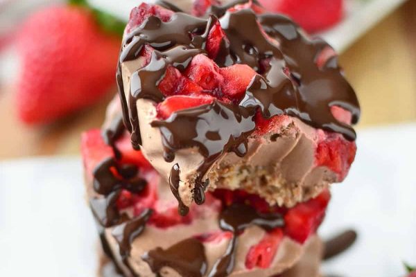 A stack of chocolate covered strawberries on a plate.
