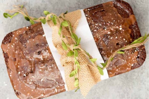 A loaf of chocolate cake wrapped in twigs and twine.