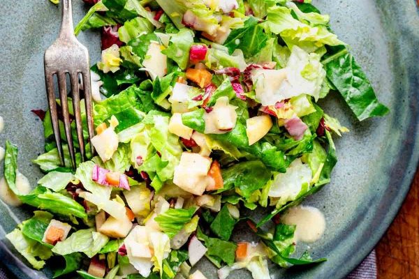 A plate with a salad and a fork on it.