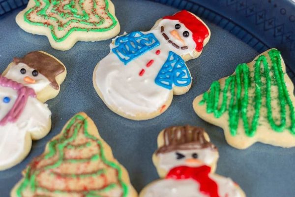 A plate of traditional Christmas desserts decorated with snowmen and trees.