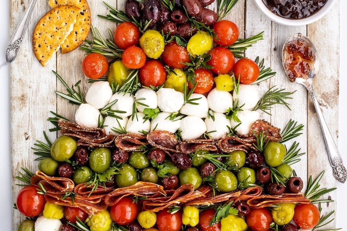 A Christmas tree adorned with olives, tomatoes, and crackers, resembling a delightful charcuterie board.