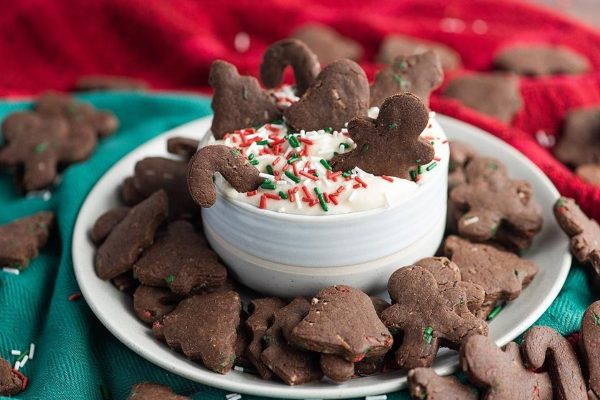 Christmas gingerbread cookies on a plate with whipped cream and chocolate drizzle.