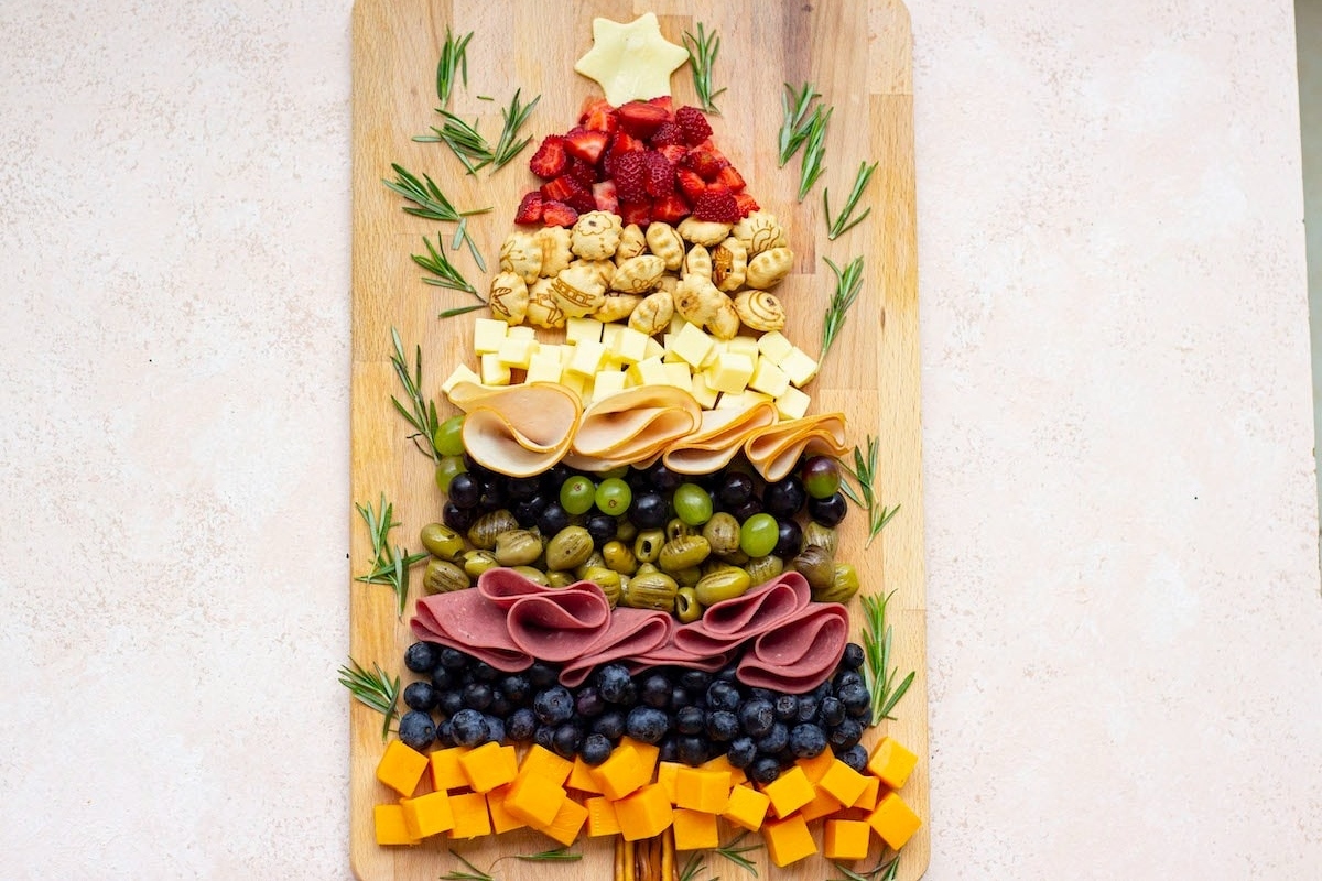 A Christmas charcuterie board featuring a festive arrangement of cheese and fruit on a wooden board.