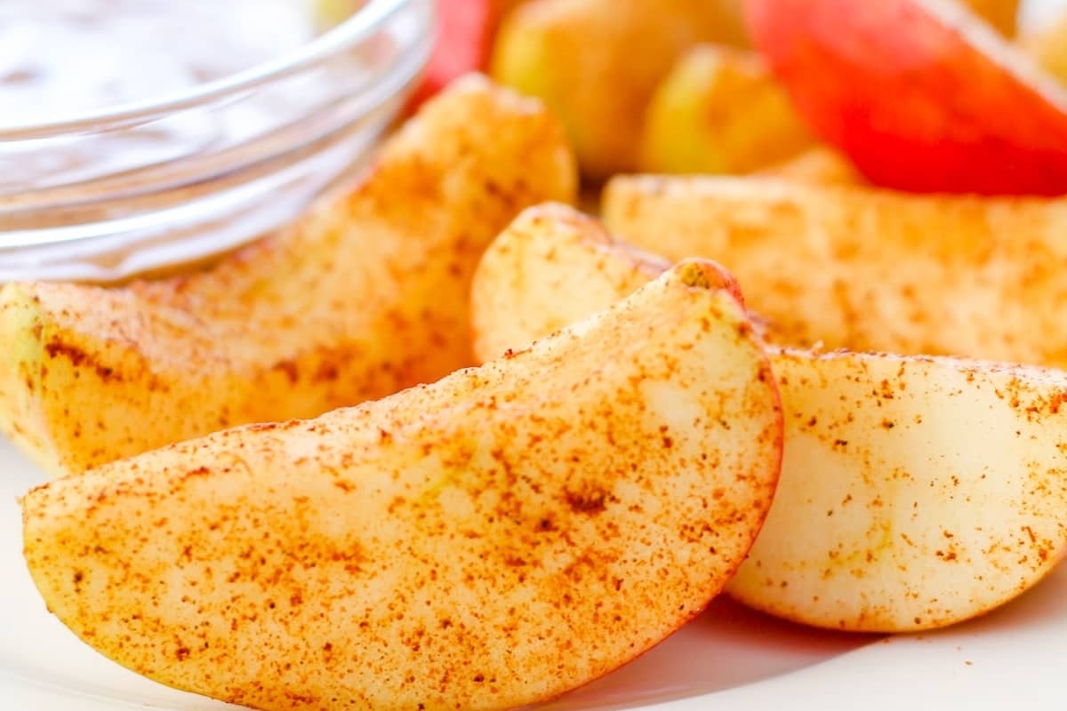 A delightful plate of beautifully sliced apples sprinkled with a generous amount of cinnamon and a touch of sugar.