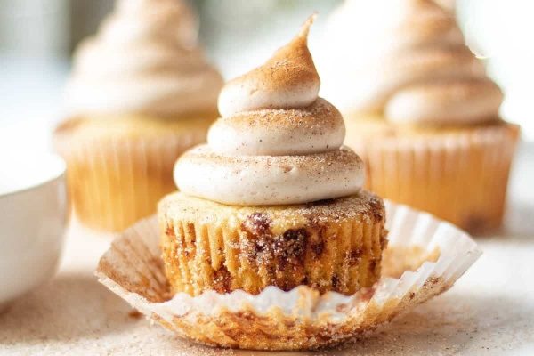 Christmas-themed cupcakes topped with whipped cream and a cup of coffee.