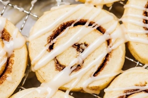 Cinnamon rolls on a cooling rack, drizzled with icing.