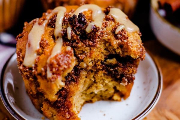 A cinnamon roll muffin with a bite taken out of it on a plate.