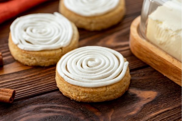 A group of cookies with icing and cinnamon on a wooden table.