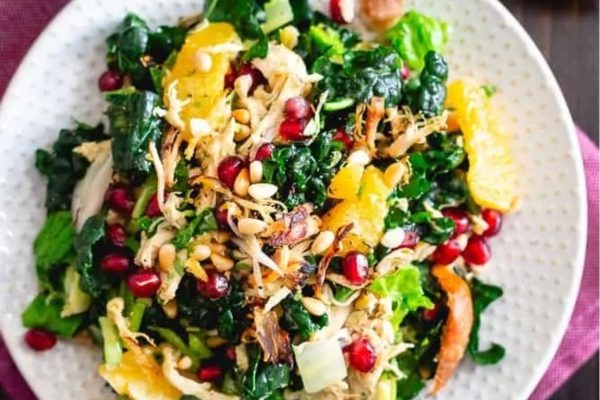 Kale salad with chicken, pomegranate, and oranges.