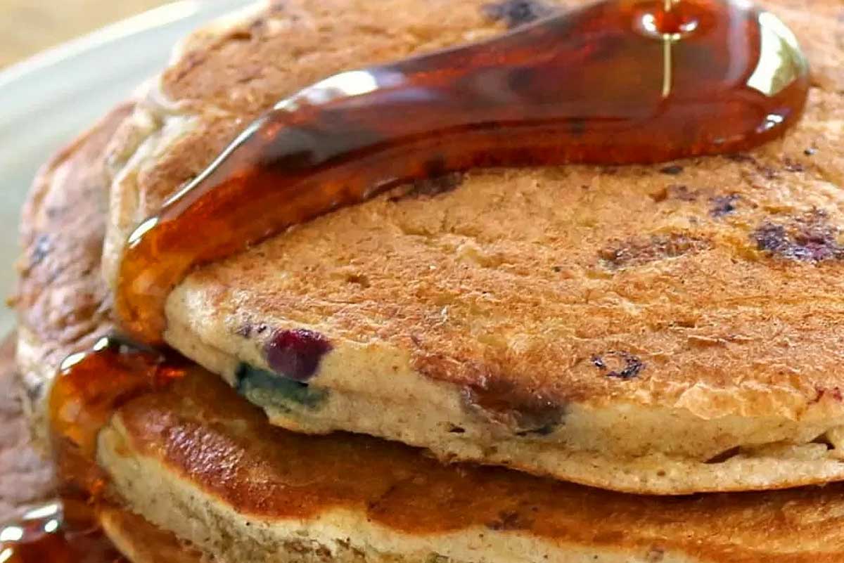 A stack of blueberry pancakes with syrup on top.