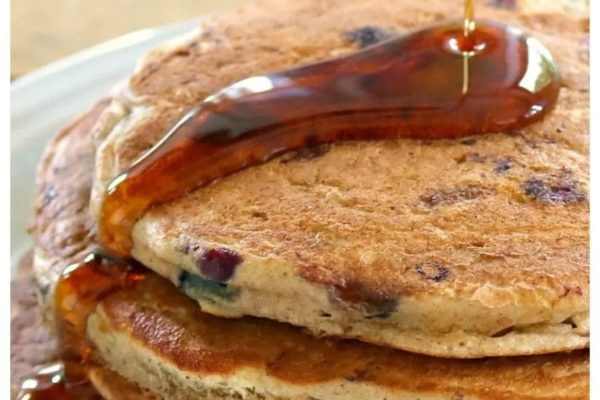 A stack of blueberry pancakes with syrup on top.