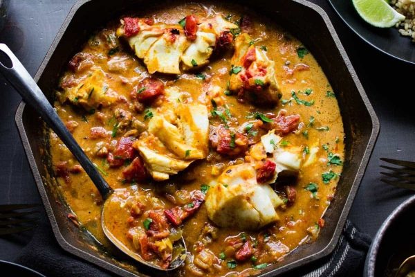 A bowl of curry with a spoon on a table.