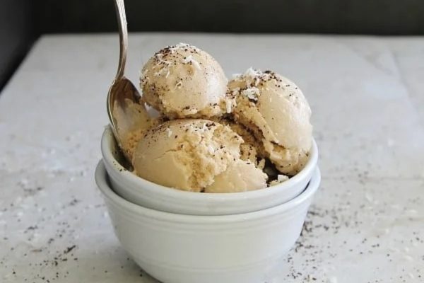 Three scoops of coconut ice cream in a white bowl.