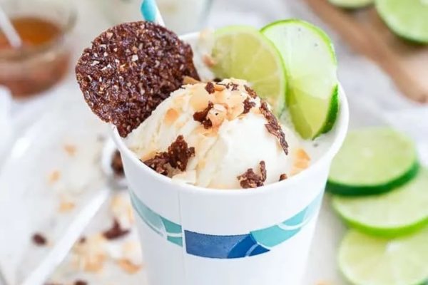 A cup of coconut ice cream with a lime wedge on top.