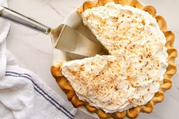 Coconut cream pie with a slice taken out.