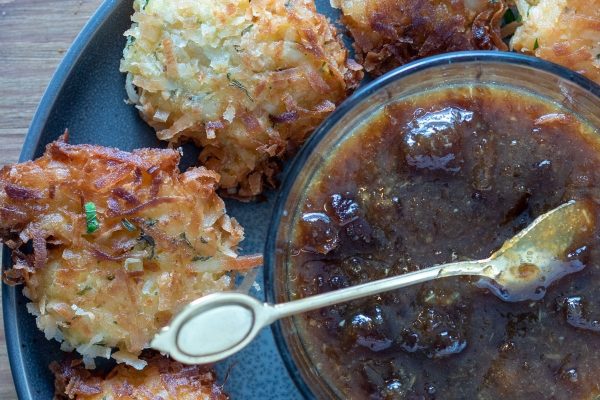 A plate of fried pastries and sauce on a black plate.