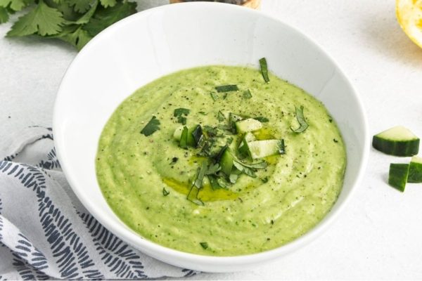 A bowl of refreshing green hummus with crisp cucumbers and zesty lemons.
