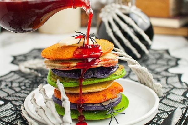 A stack of pancakes with syrup being poured over them.