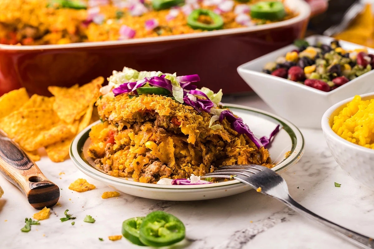 A plate of Mexican casserole with ground turkey, tortilla chips, and salsa.