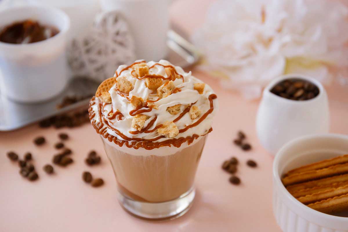 A cup of coffee with whipped cream and cinnamon sticks.