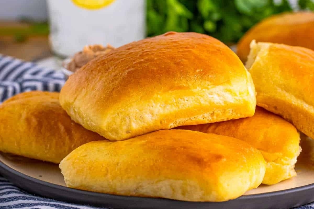 Bread rolls on a basket next to a glass of water.