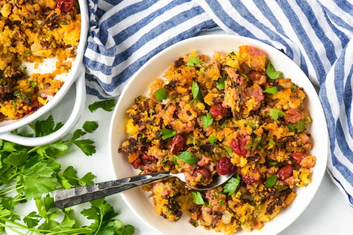         Two bowls of stuffing on a table next to a blue and white striped tablecloth.