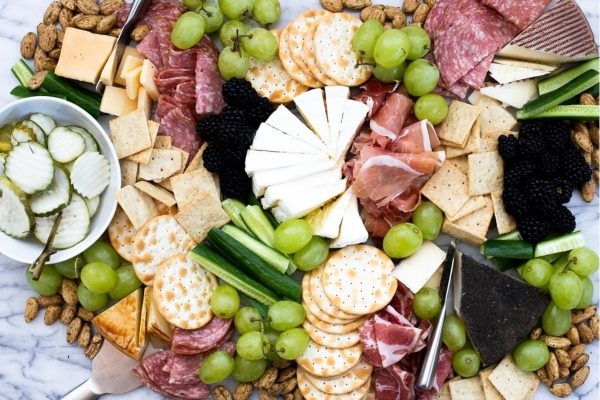 A festive charcuterie board piled high with a variety of cheeses, crispy crackers, and vibrant grapes - perfect for Christmas gatherings.