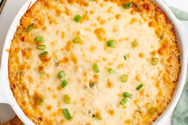 Cheesy dip with green onions in a white dish.