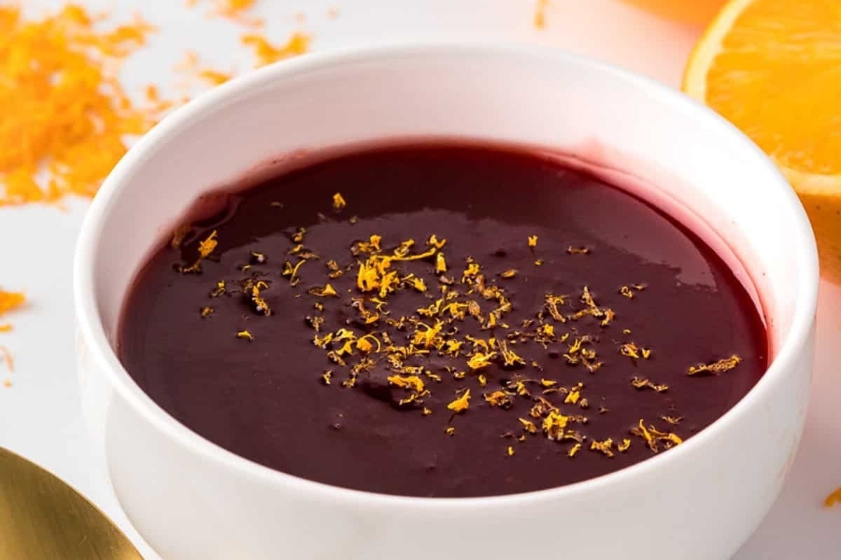 Beetroot soup with cranberry sauce in a white bowl.