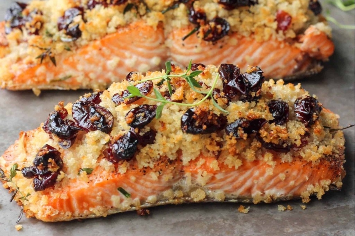 A delicious dinner featuring two salmon fillets, generously topped with cranberries and aromatic herbs.