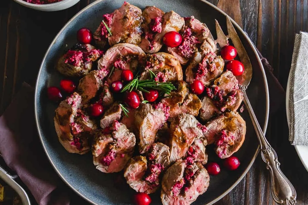 A plate of Turkey with cranberries and rosemary.