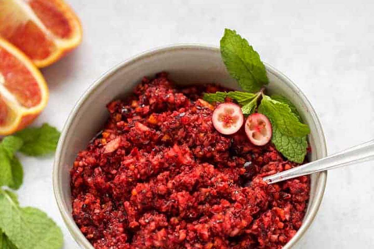 A bowl filled with a delicious vegan mixture of red grapes and oranges, perfect for the Thanksgiving table.