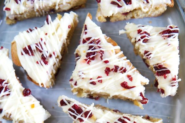 Cranberry bars with white icing on a baking sheet.