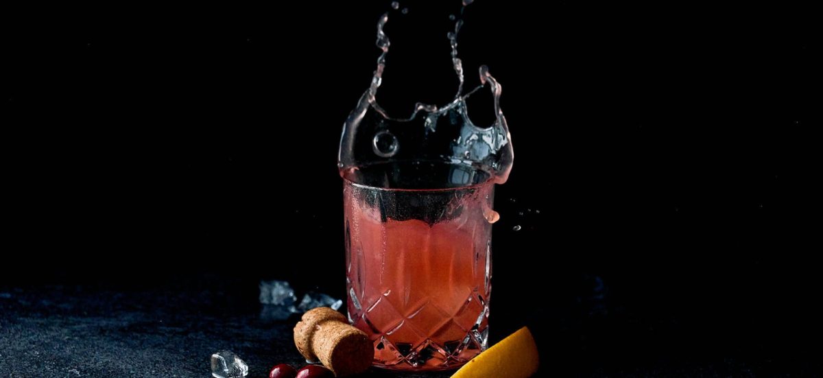 A champagne cocktail with a splash of liquid on a black background.