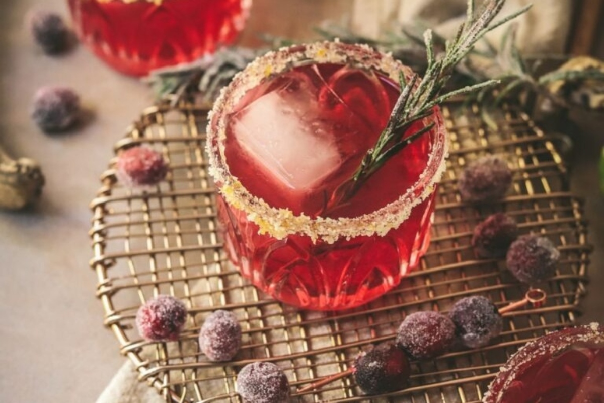 A festive Christmas cocktail featuring cranberries and sprigs of rosemary.