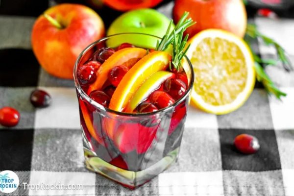 A glass of cranberry sangria with apples and rosemary.