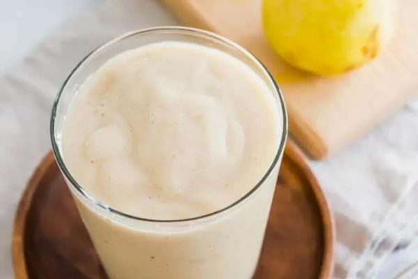 A glass of lemon smoothie with a slice of lemon on top.