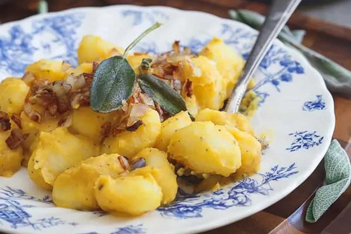 A white and blue plate with gnocchi, potatoes, and sage.