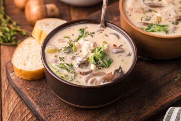 Two bowls of soup with mushrooms and bread on a wooden table, showcasing the versatility of soups with a few ingredients.