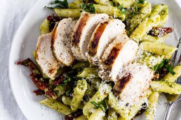 A plate of pesto pasta with chicken and parmesan.