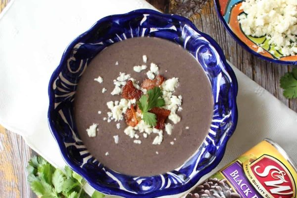 A bowl of black bean soup with cheese and bacon.