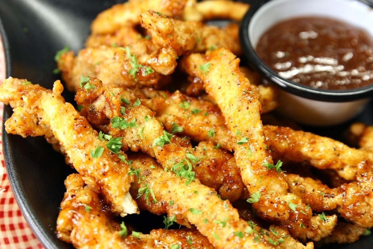 Crispy fried chicken fingers served with a delectable dipping sauce on a plate.