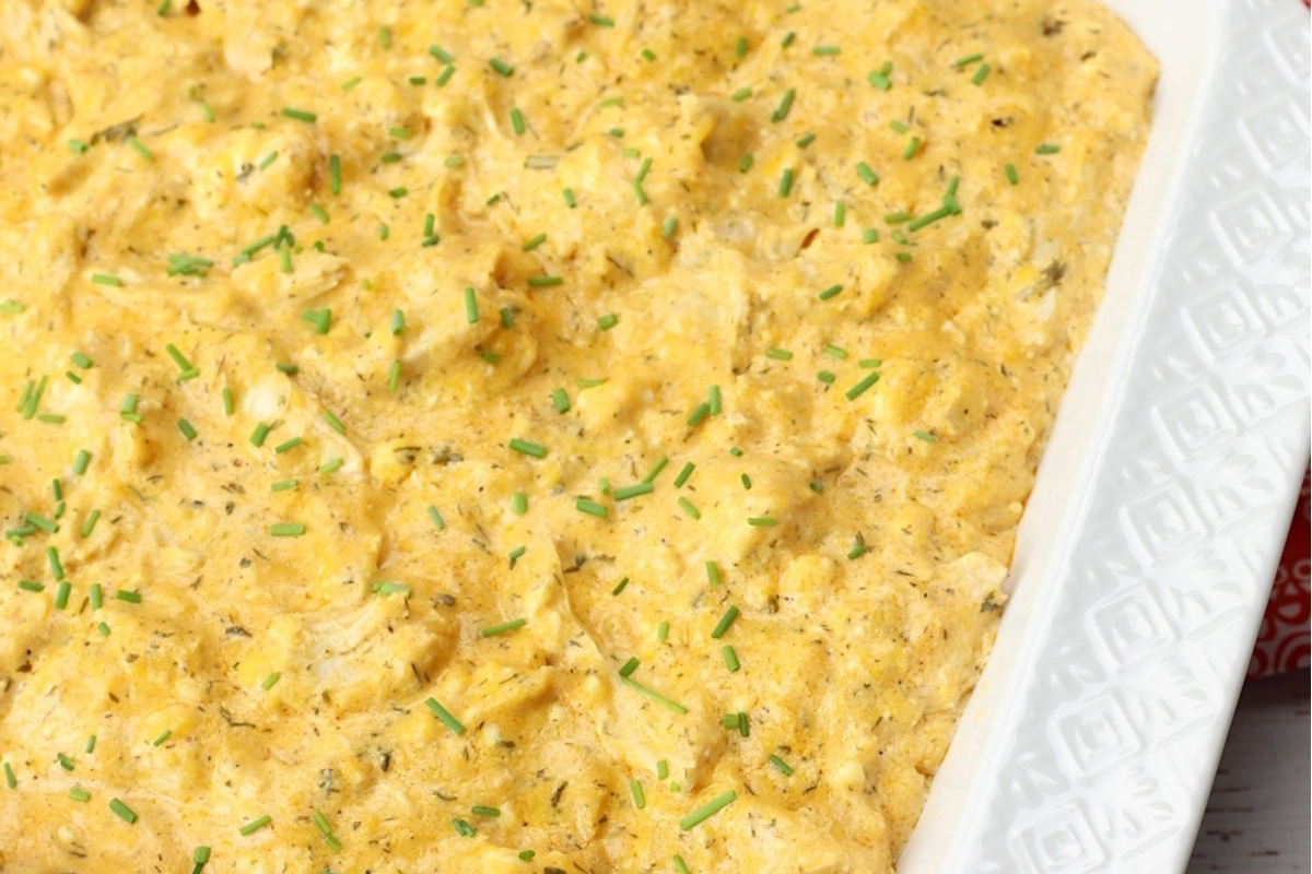A slow cooker filled with chicken and chives.