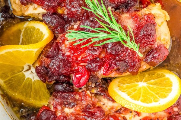 Chicken with cranberry sauce and orange slices.