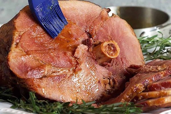 A ham on a plate with a blue spatula.
