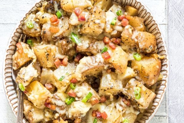 Cheesy potatoes in a bowl on a wooden table.