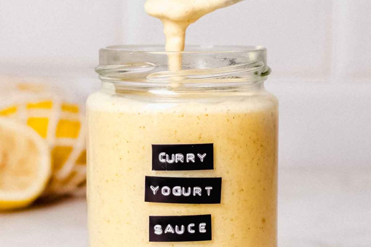 Curry yogurt sauce recipe in a jar with lemons.