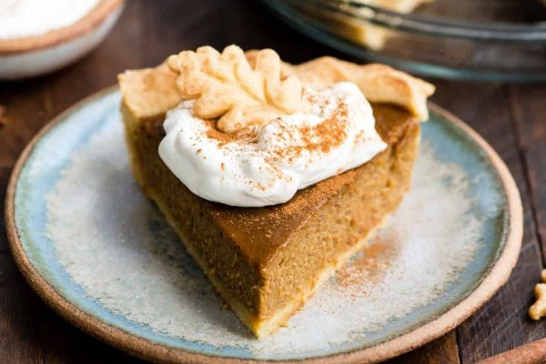 A slice of pumpkin pie with whipped cream on a plate.