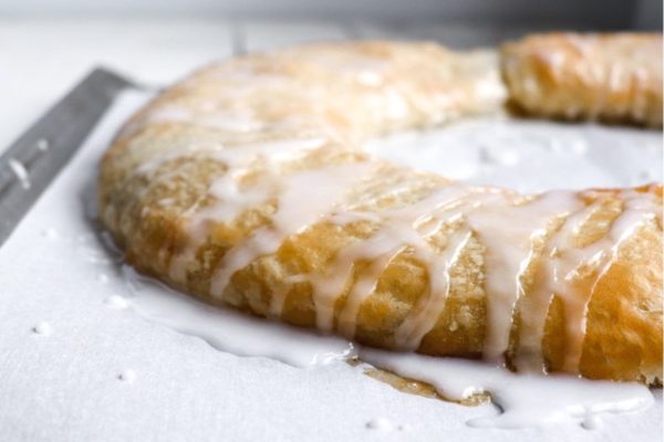 A pastry with icing and a knife on top.